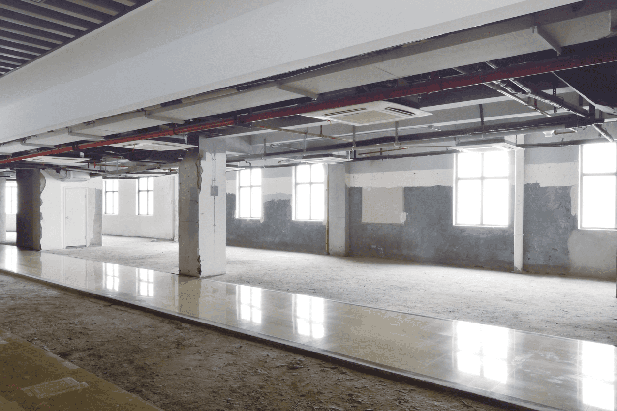 A large empty room with windows and concrete floors.