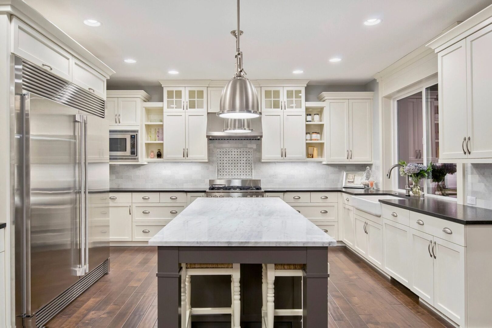 A large kitchen with white cabinets and wooden floors.